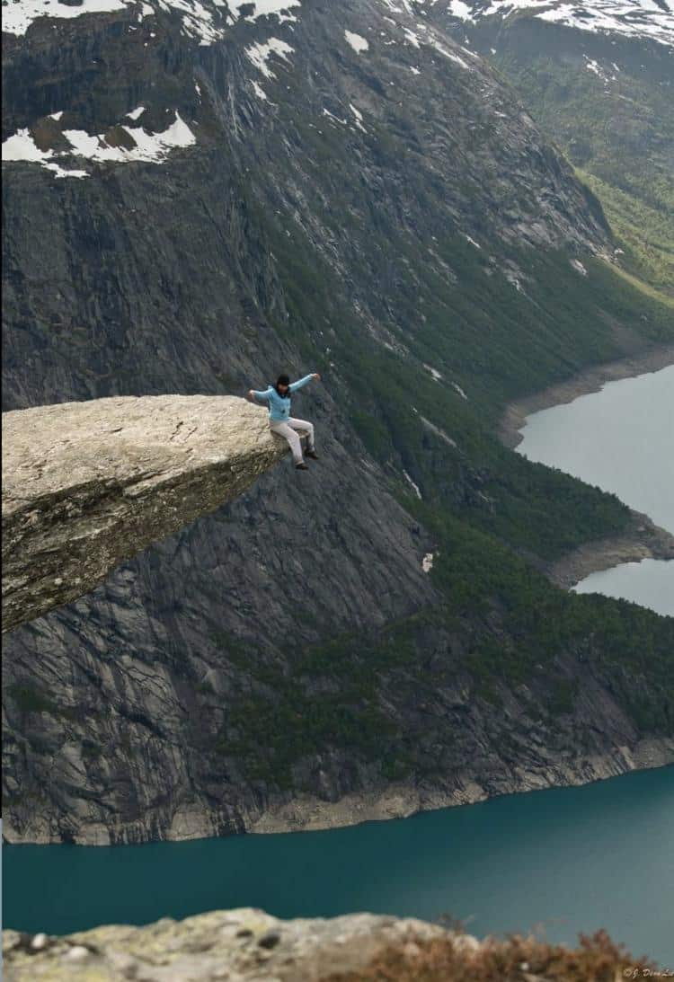 Sitting on the Trolltunga rock in Norway High Place